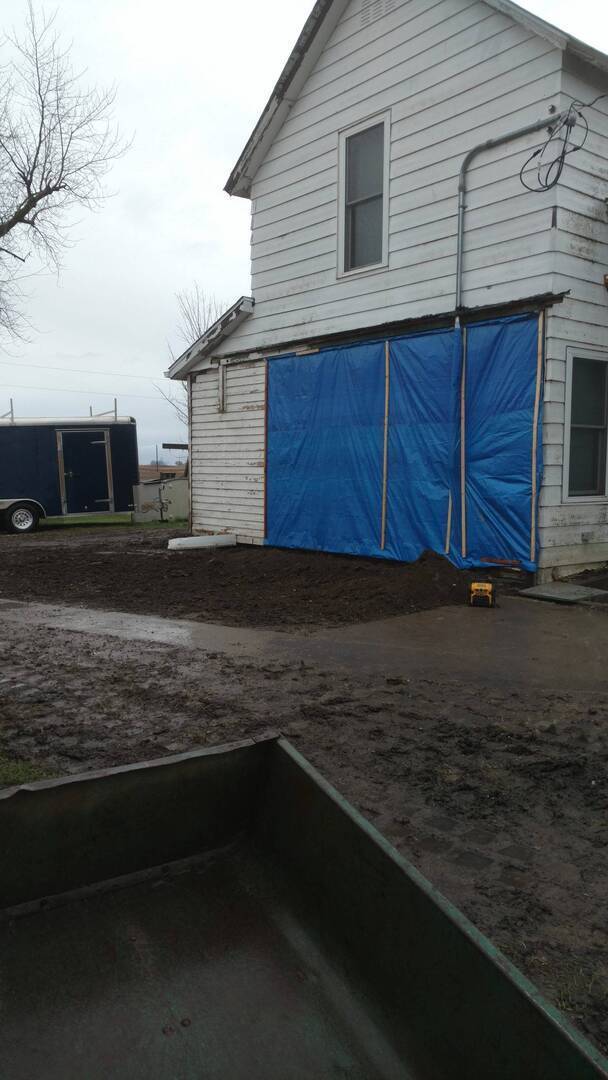 The back of the Elkhart farmhouse with a tarp over part of the house after getting its crawlspace foundation replaced by Basement RX.