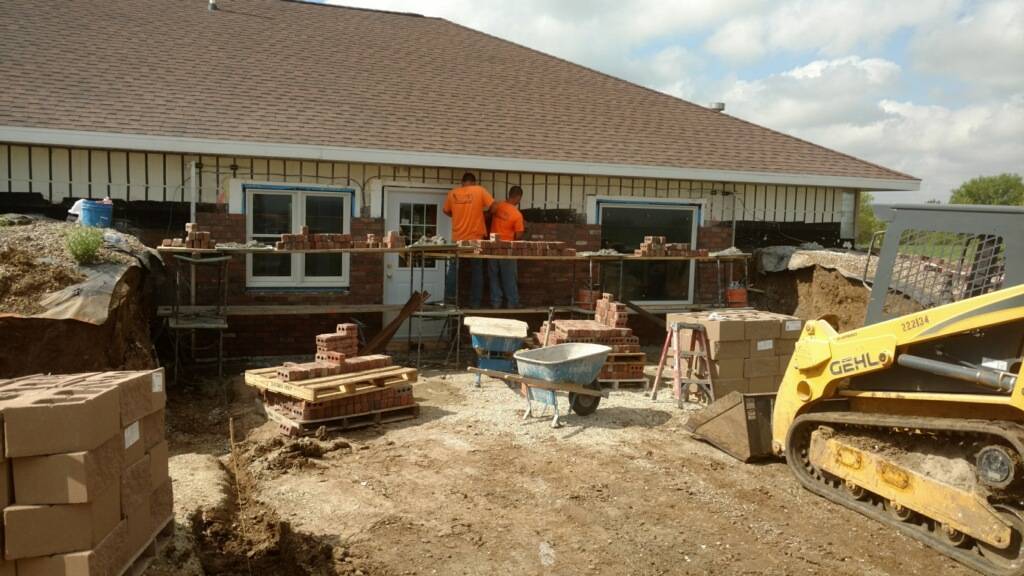 Two Basement RX journeymen masons working on laying brick walls of a house.